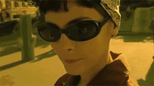 a woman wearing sunglasses and a bandana is walking down the street .