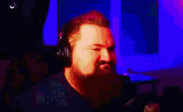 a man with a beard is wearing headphones in a dark room .