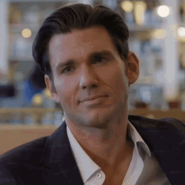 a man in a suit and white shirt is sitting at a table looking at the camera .