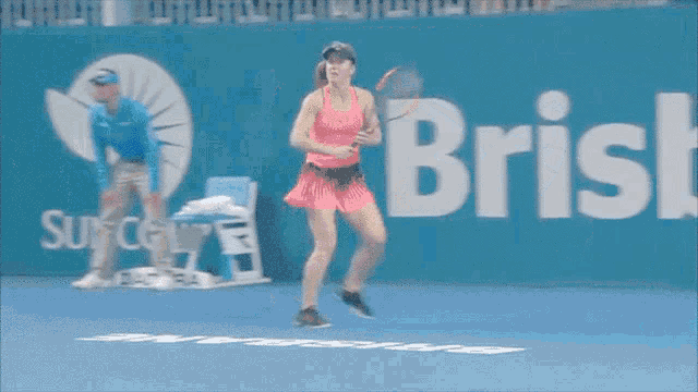 a woman in a pink dress is playing tennis in front of an ad for suncor