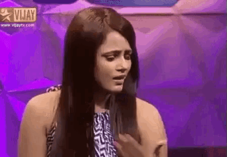 a woman with long hair is making a funny face while sitting on a stage .
