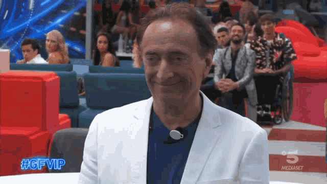 a man in a white jacket is smiling in front of a screen that says #gfvip on it