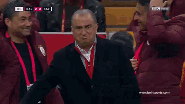 a man is wearing a red medal around his neck while standing on a soccer field .