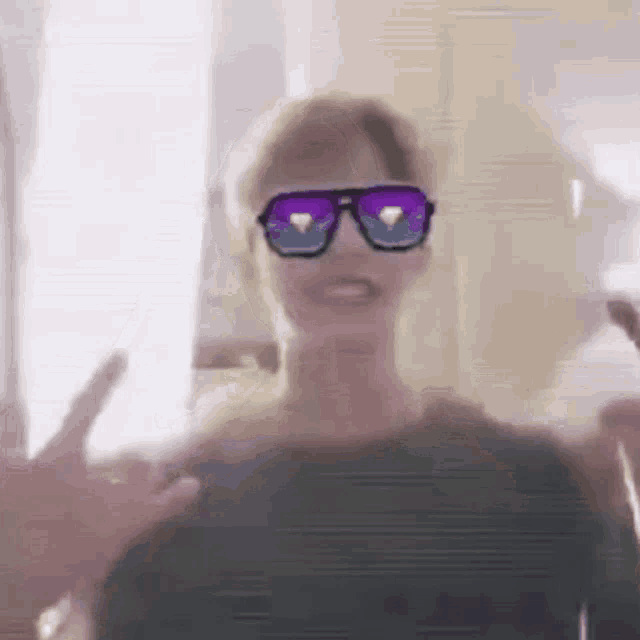 a man wearing sunglasses is giving a peace sign while standing in front of a window .