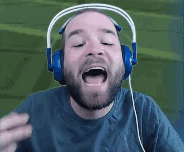 a man with a beard wearing headphones with his mouth wide open