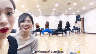 a group of women are sitting in chairs in a room and one of them says `` her honest reaction '' .