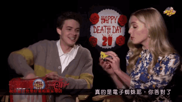 a man and woman are sitting in front of a sign that says happy death day
