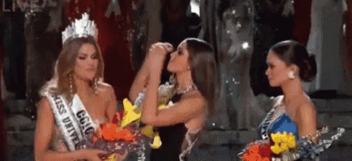 three women are standing next to each other on a stage at a pageant .