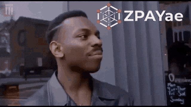 a man is standing in front of a sign that says " zpayae "