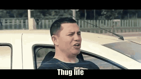 a man is sitting in the driver 's seat of a white car and says thug life .