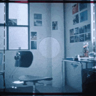 a corner of a room with pictures on the wall and a chair in the foreground