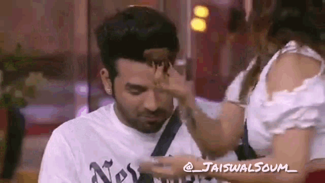 a woman is touching a man 's face in a room .