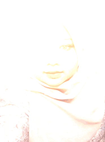 a woman in a hijab looks at the camera with sparklers behind her