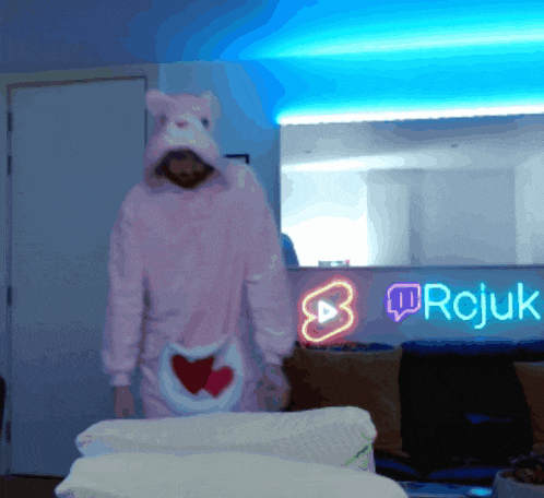 a man in a pink bear costume stands in front of a neon sign that says rcjuk