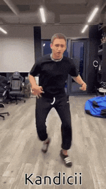 a man in a black shirt is jumping in a room with the word kandicii written on the floor