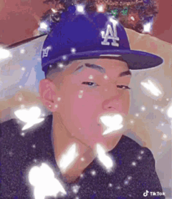 a young man wearing a la dodgers hat is looking at the camera .