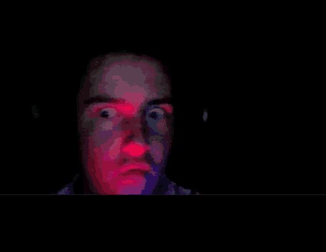 a man 's face is lit up with red and green lights in the dark