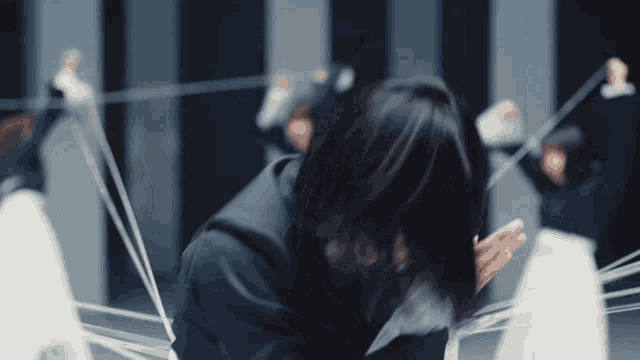 a woman in a black suit is surrounded by white ropes