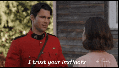 a man in a red uniform is talking to a woman and says i trust your instincts