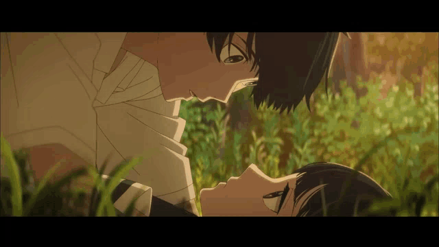 a man and a woman are laying in the grass and looking at each other