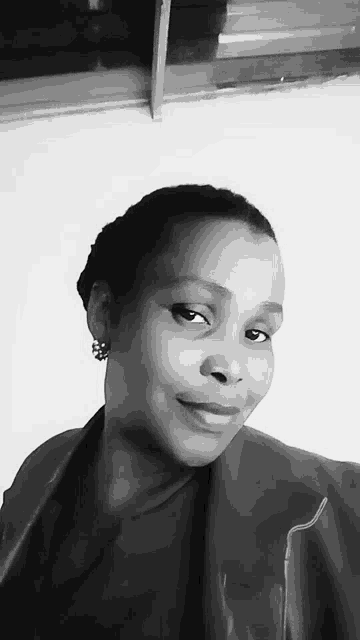 a black and white photo of a woman wearing a leather jacket and earrings