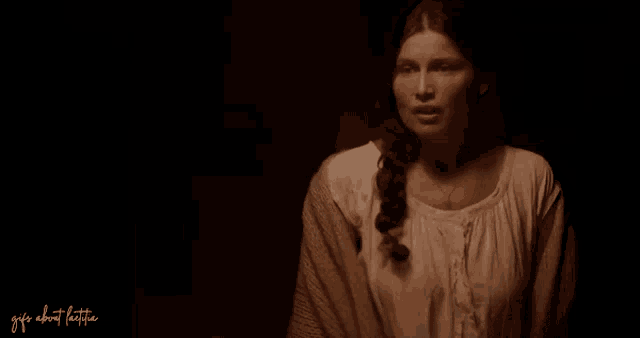 a woman in a braided ponytail is standing in a dark room ..