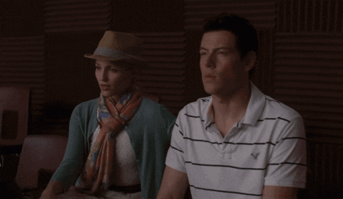 a man and a woman are standing next to each other and the woman is wearing a hat and scarf