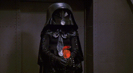 a man in a brown jacket is holding a light saber in front of a wall with a button on it .