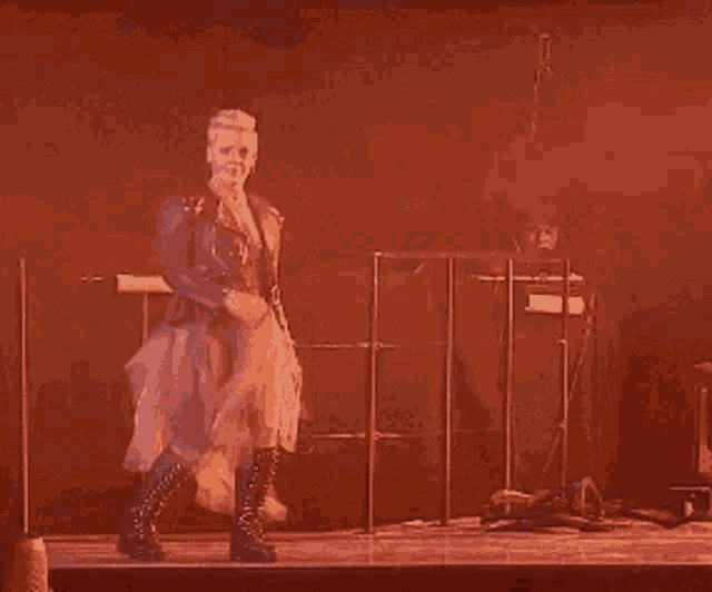 a woman wearing a tulle skirt and black boots is dancing on a stage