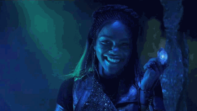 a woman with braids is smiling and holding a blue object in her hand