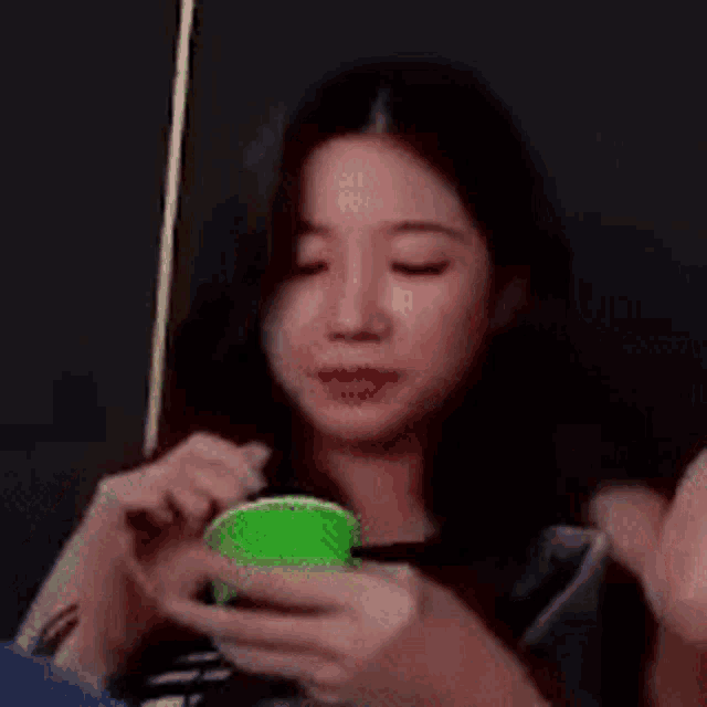 a woman is holding a green cup and a stick in her hair .