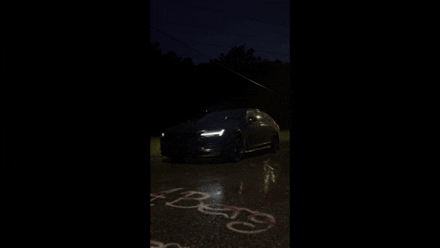 a car is parked in a dark parking lot with the word beats written on the road