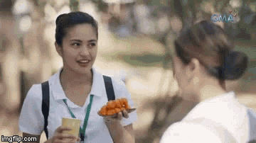 two women are talking to each other while one of them is holding a plate of food .