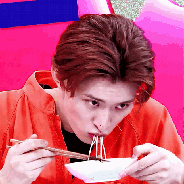a young man eating noodles with chopsticks from a bowl