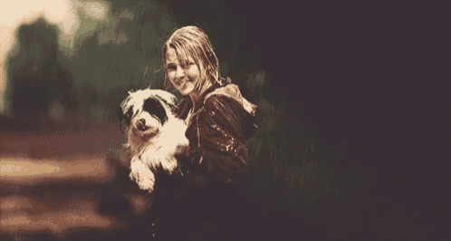 a young girl is holding a small dog in the rain .