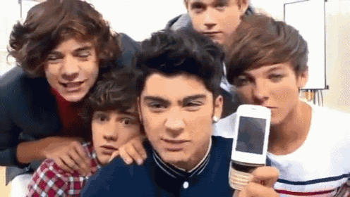a group of young boys are posing for a picture and one of them is holding a cell phone