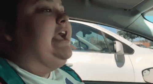 a man is singing while driving a car .