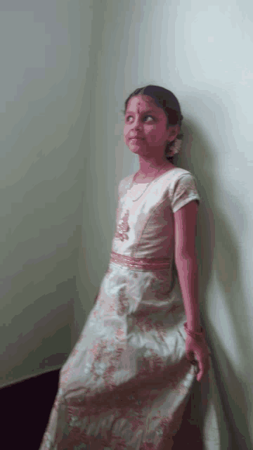 a girl leaning against a wall in a white dress
