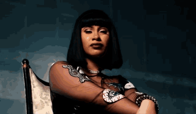 a woman is sitting in a chair with her arms crossed and looking at the camera