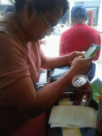 a woman sits at a table with a can of soda and a cell phone