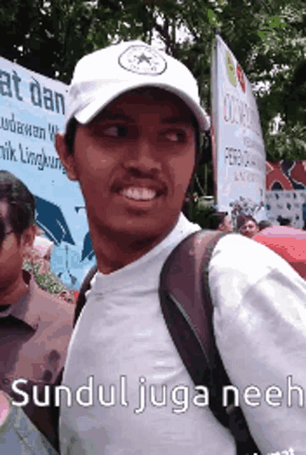 a man wearing a white hat with the words sundul juga neeh on the bottom
