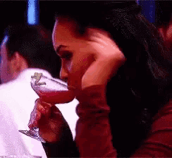 a woman drinking from a martini glass with her hand on her face