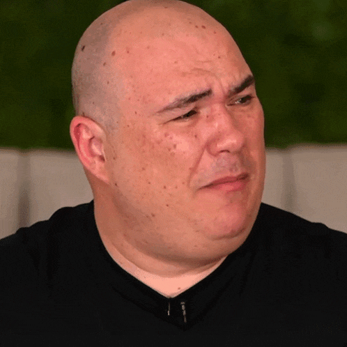 a bald man wearing a black shirt with a zipper on the front