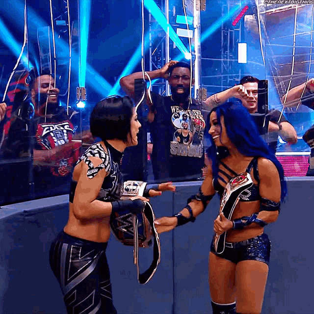 two female wrestlers are holding their belts and one has a shirt that says we are the champions