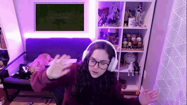 a woman wearing headphones and glasses is sitting in front of a couch in a living room .