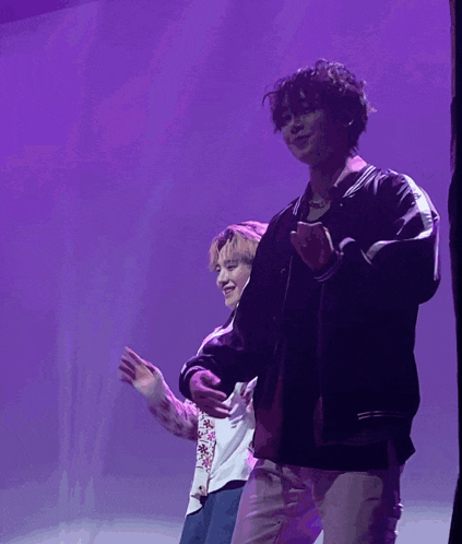 a man in a black jacket is dancing with another man in a white shirt