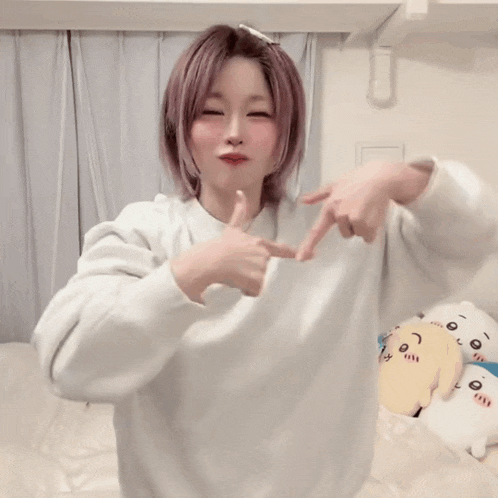 a woman with pink hair is wearing a white sweatshirt that says bad girls on it