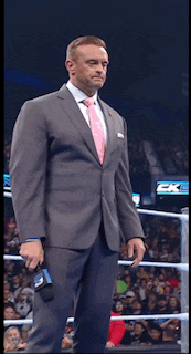 a man in a suit and tie is standing in a ring holding a microphone with the number 3 on it