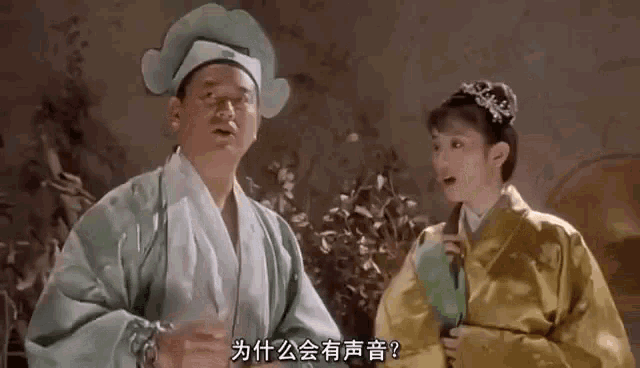 a man in a green robe and a woman in a yellow dress are standing next to each other and talking to each other .