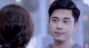 a man and woman are looking at each other and the man is wearing a grey sweater .